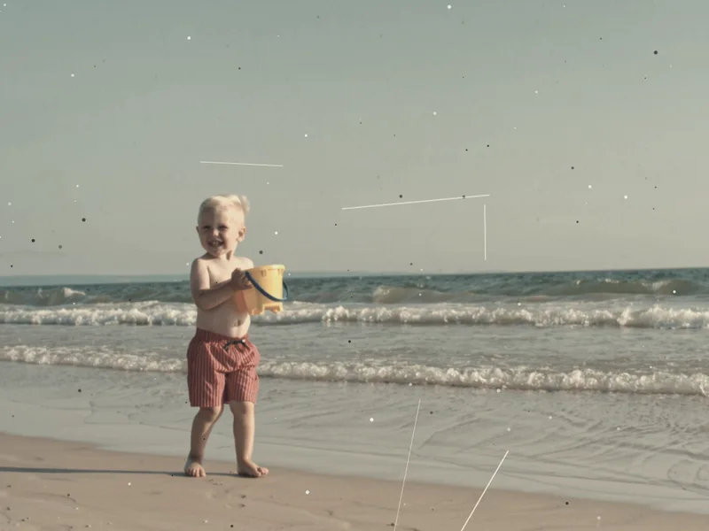 Old color photo of a small child on a beach, faded and low in contrast, used to check an AI photo editor