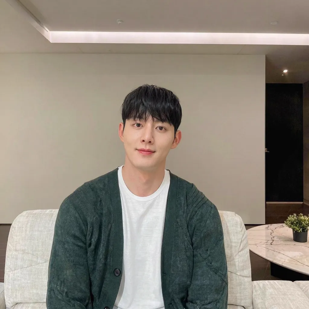 Young man in a green cardigan on a sofa in a living room under flat, even indoor light